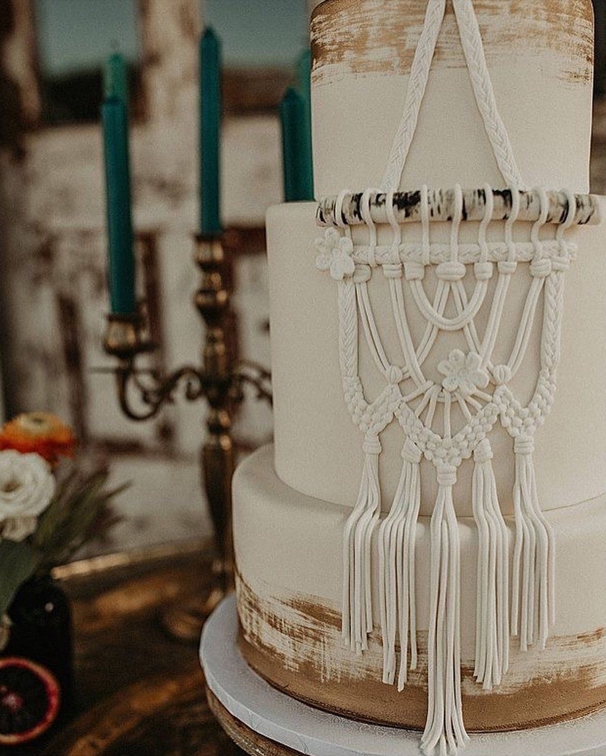 Wedding cake with a piped macrame hanging down the front and brushed gold tiers