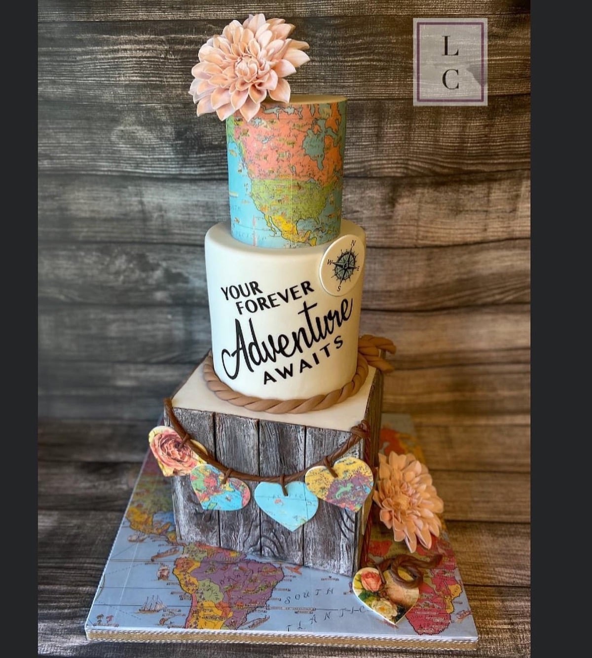 Adventure-themed wedding cake with map tiers, a wood grain tier, and Your Forever Adventure Awaits script