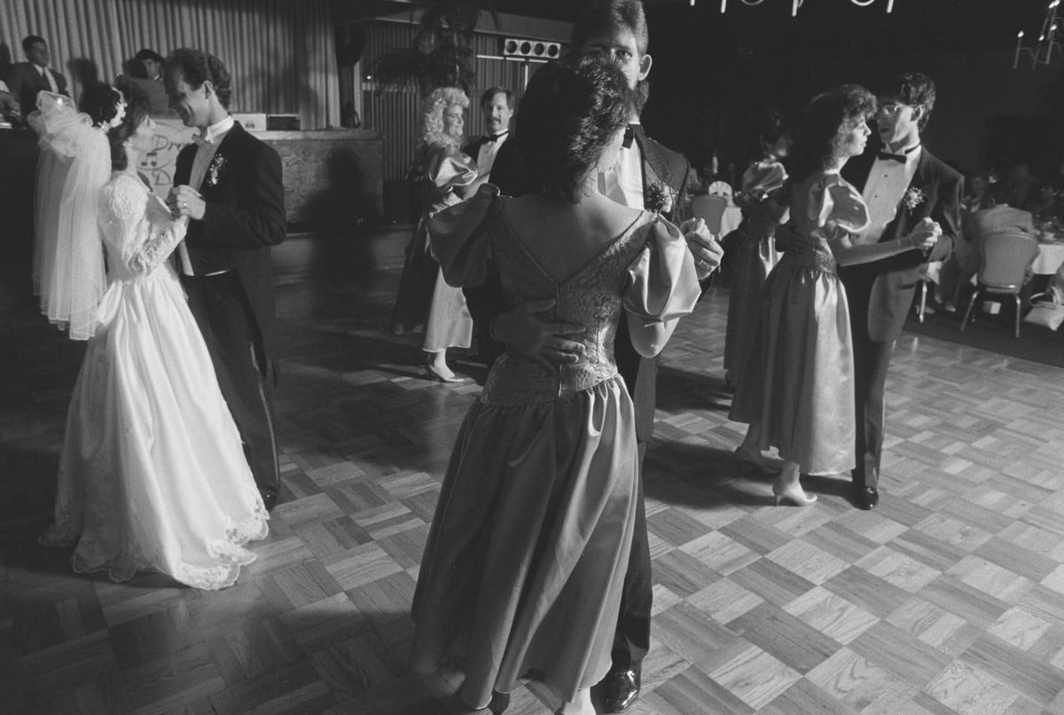 Couples slow dancing at a 1989 wedding reception, bride and groom at left, bridesmaids in puffed-sleeve dresses
