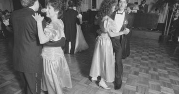 Wedding guests dancing at a 1989 reception, big permed hair and puffed satin sleeves, the bride dancing in the background