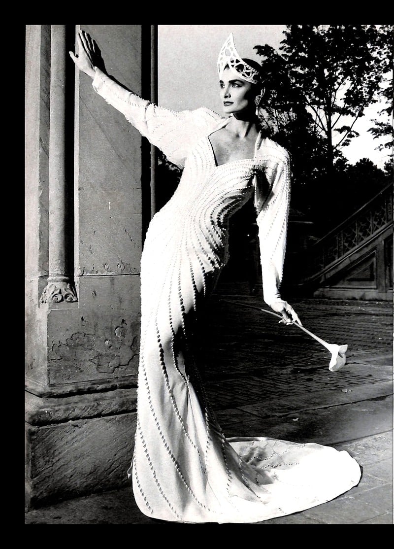 1988 Yumi Katsura advertisement in black and white: model in a beaded column sheath wedding gown with a crown headpiece, holding a bouquet