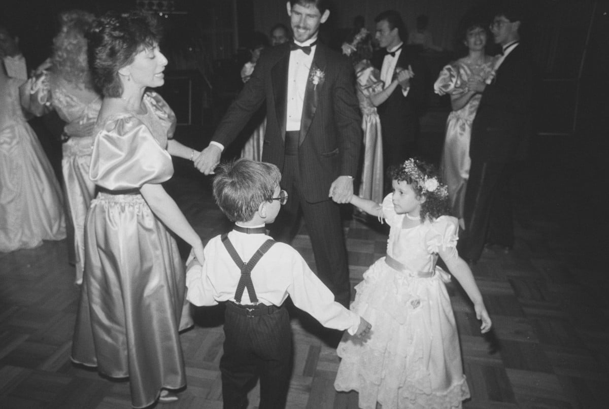 The wedding party dancing in a circle with the ring bearer and flower girl at a 1989 reception