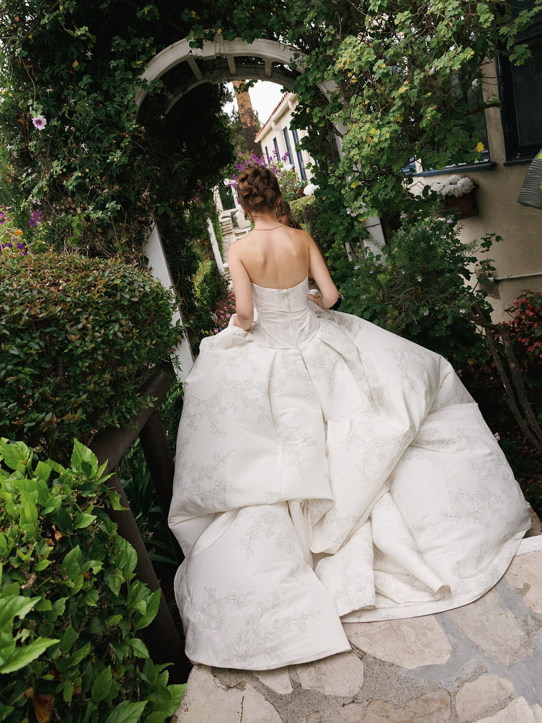 Baylee walking under a rose-covered garden arch at La Venta Inn