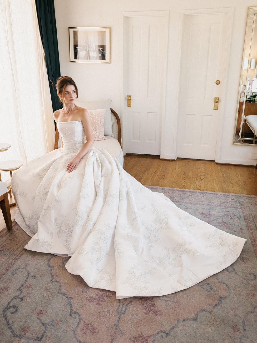 Baylee seated with her ivory ballgown and train spread across the rug