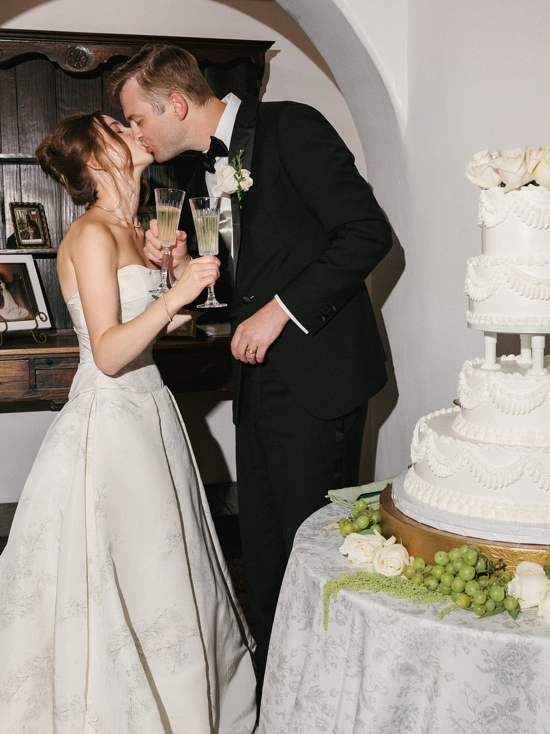Baylee and Avery kiss with champagne in hand after cutting their wedding cake