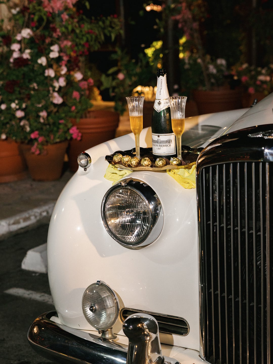 Champagne and glasses on the hood of the couple's vintage Bentley getaway car