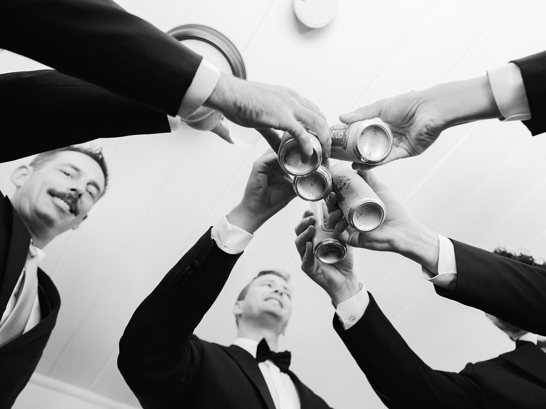 Overhead black and white shot of Avery and his groomsmen toasting with beers