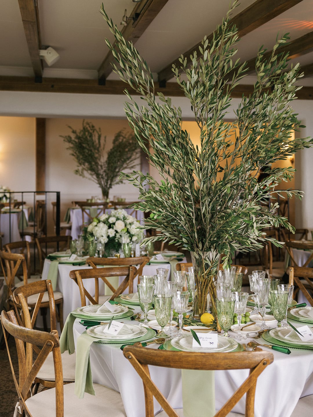 Reception tables at La Venta Inn with tall olive branch centerpieces and green accents