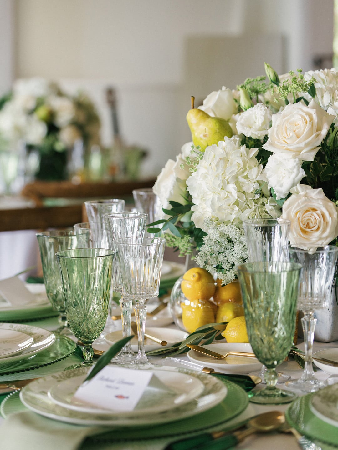 Tablescape with green goblets, white hydrangeas, roses, and fresh lemons
