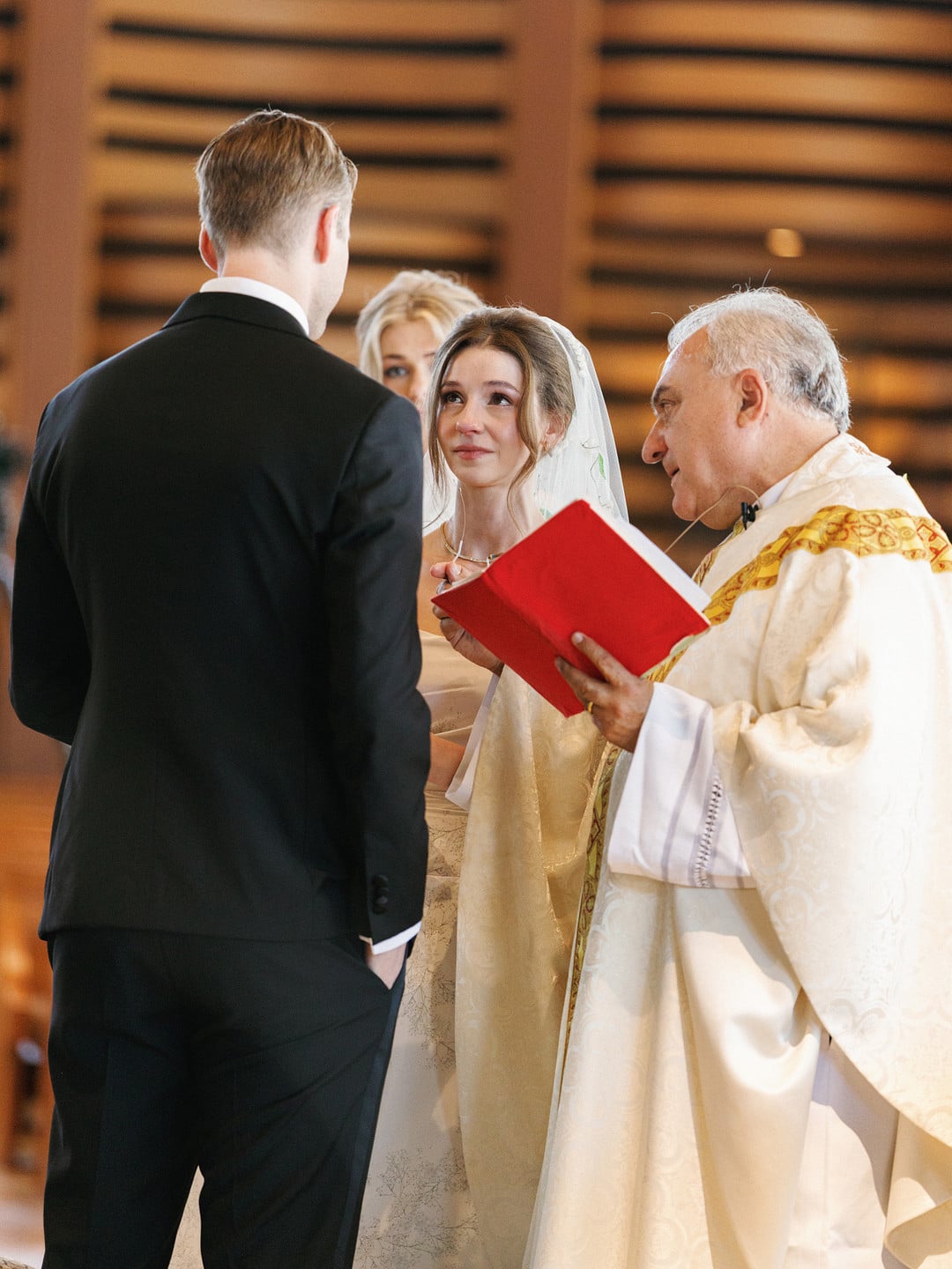 Baylee looks at Avery as the priest reads during their Catholic wedding ceremony