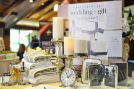 Wedding registry display with towels, candles, picture frames, a clock, and tabletop accessories