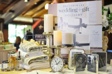 Wedding registry display with towels, candles, picture frames, a clock, and tabletop accessories