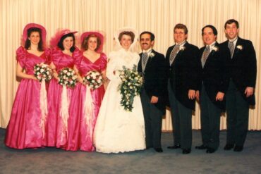 1988 wedding party: bride and groom with bridesmaids in hot-pink satin puff-sleeve dresses and groomsmen in tails