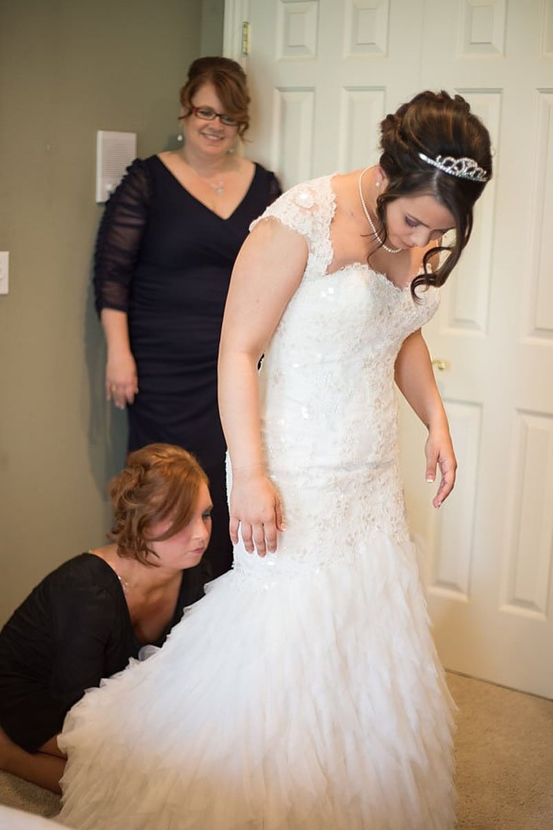 Mother in a navy dress fastening the bride's gown in the getting-ready room