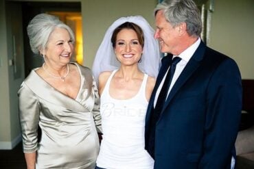The mother of the bride in a champagne gown smiling with the bride and her father before the ceremony