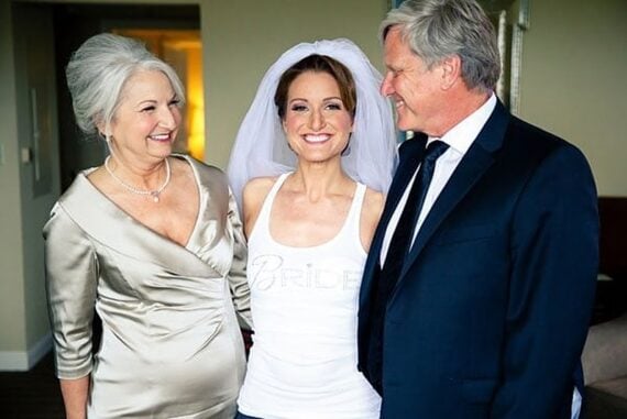 The mother of the bride in a champagne gown smiling with the bride and her father before the ceremony