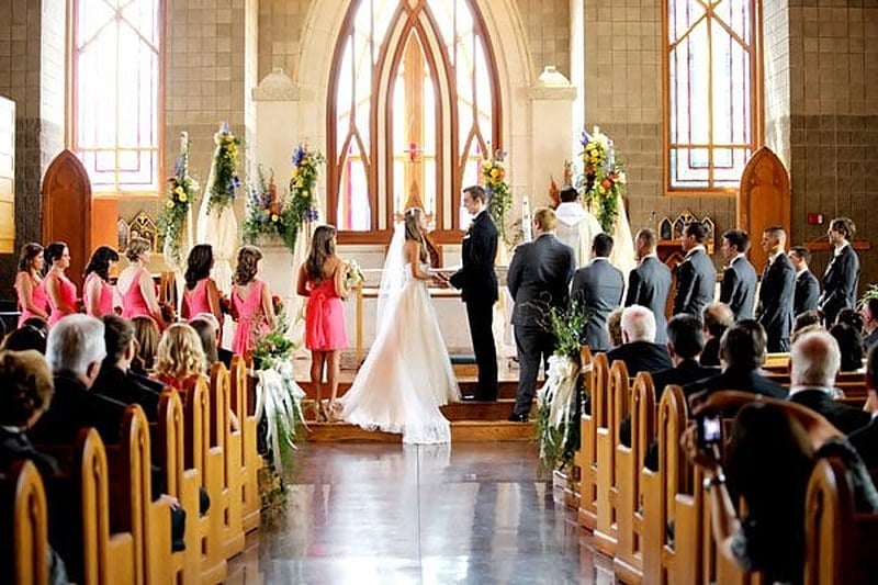 Guests filling the pews of a wooden chapel during a wedding ceremony