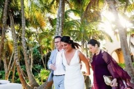 A smiling bride and groom walking through their guests after a beach ceremony in Tulum