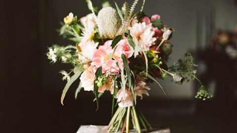 Red, blush and white wedding bouquet with anemones and greenery on a wooden stool