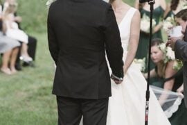 Bride and groom exchanging vows under a greenery arch