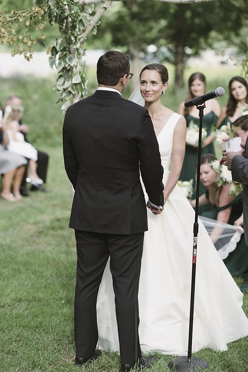 Bride and groom exchanging vows under a greenery arch
