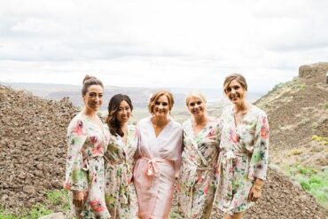 Bridesmaids in floral robes laughing together in a vineyard