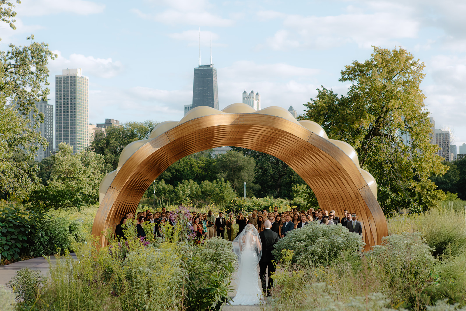 Wedding ceremony at the Honeycomb arch at Lincoln Park Zoo with the Chicago skyline behind