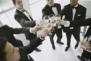 Groomsmen raising champagne glasses in a toast