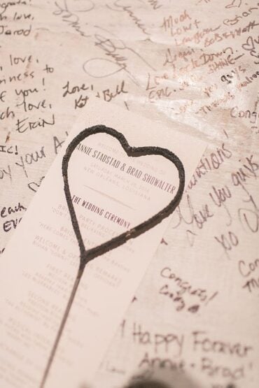 Heart-shaped sparkler resting on a signed wedding guest book