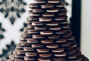 Tiered wedding cake alternative made of stacked chocolate sandwich cookies on a white cake stand with a black bow