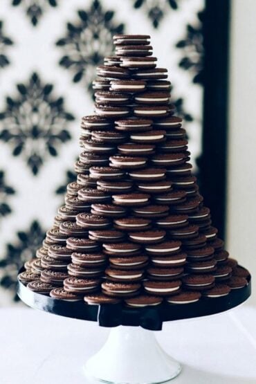 Tiered wedding cake alternative made of stacked chocolate sandwich cookies on a white cake stand with a black bow