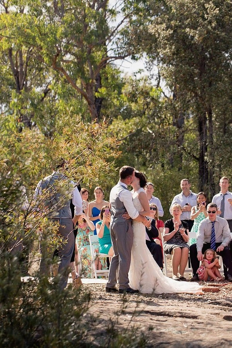 Guests holding up phones during the first kiss at an outdoor Australian wedding ceremony