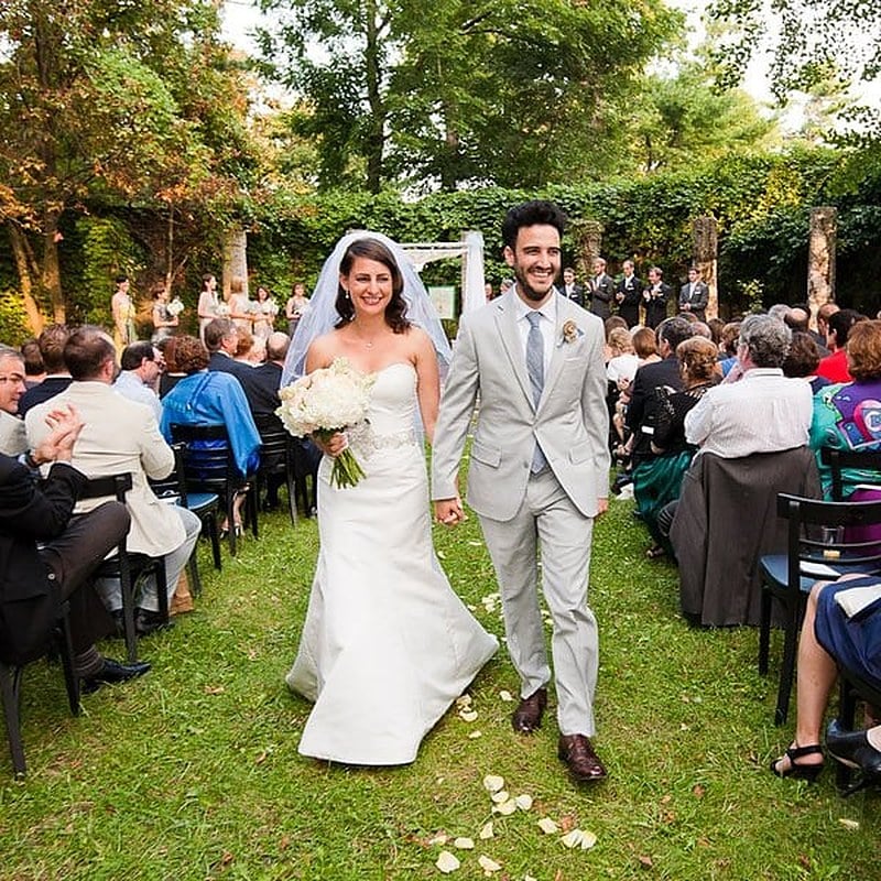 Bride and groom walking back up the aisle past seated guests after the ceremony