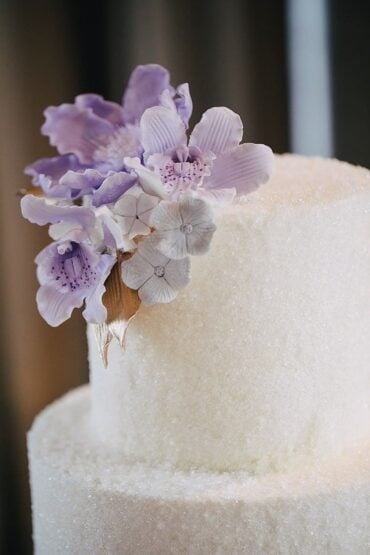 Three-tier white wedding cake with lilac sugar orchids